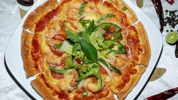 Een pizza met toppings en garnering op een bord.