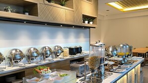 A buffet setup with various food stations, including a fruit bowl and a water dispenser. - ILLIRA Lite Praya Lombok (Praya)