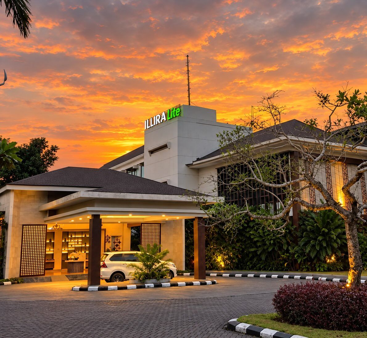 A hotel with a modern design, a covered entrance, and a car parked in front.