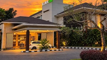 A hotel with a modern design, a covered entrance, and a car parked in front.