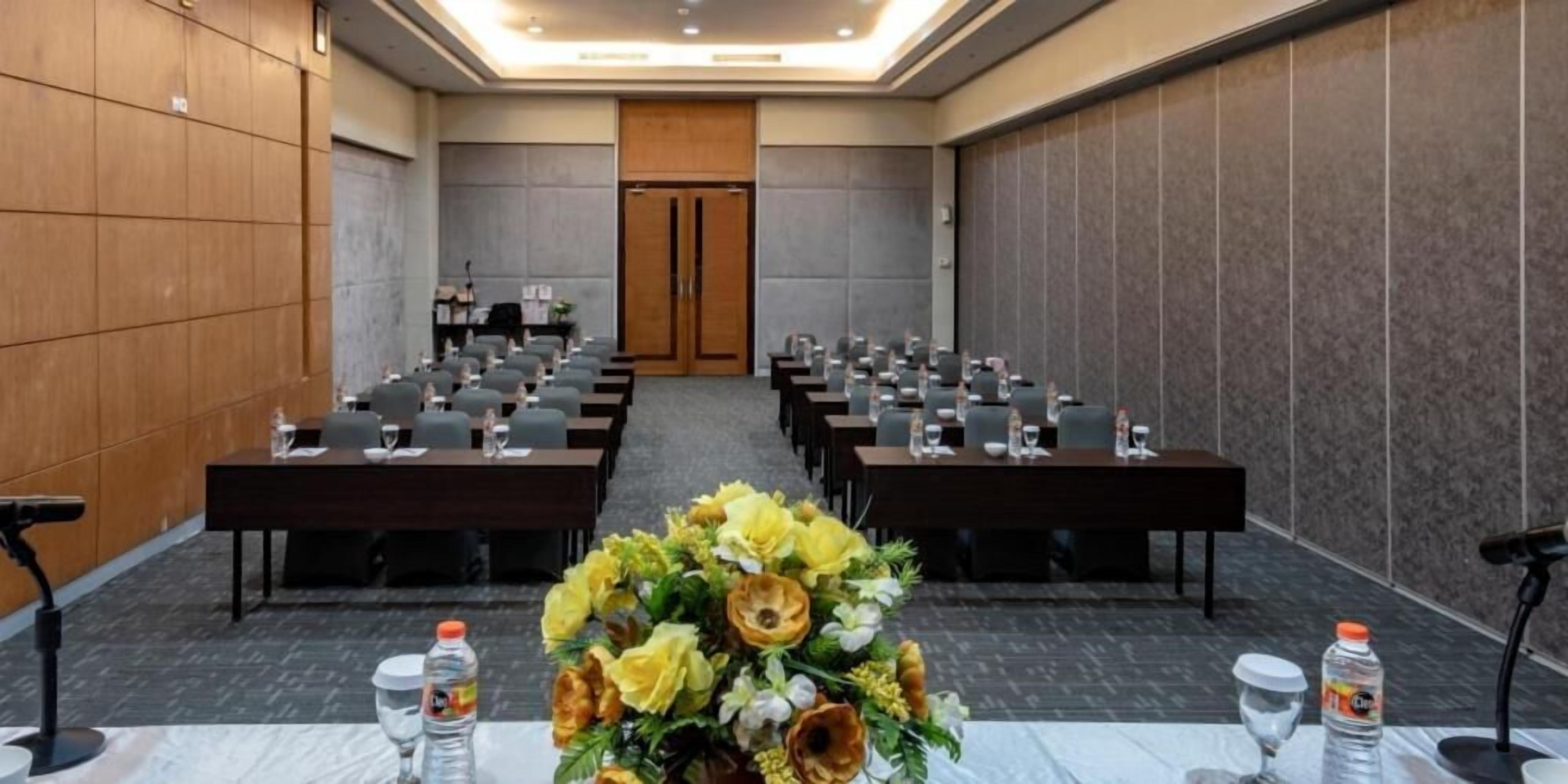 Un salón de conferencias con filas de mesas, sillas y una gran decoración floral.