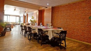 A dining area with brick walls, wooden flooring, and tables set for dining. - Hotel Mountain (Kathmandu)
