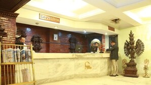 A reception area with a marble counter, a reception desk, and a statue. - Hotel Mountain (Kathmandu)