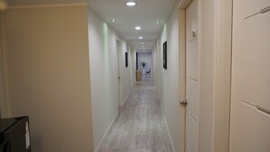 A long, narrow hallway with a wooden floor, white walls, and doors on both sides.