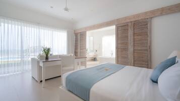 A modern bedroom with a large bed, a desk, and a view of the outdoors.