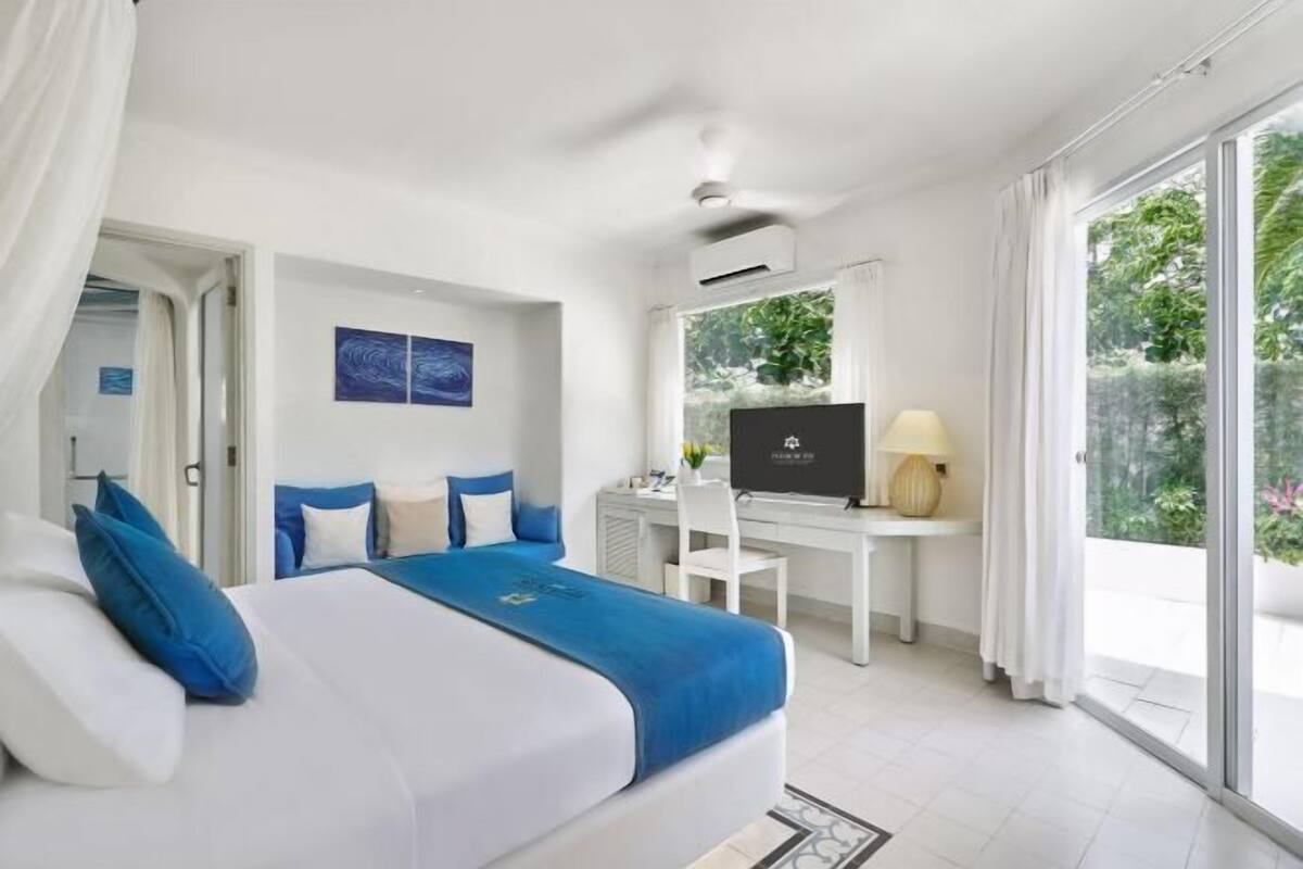 Une chambre d’hôtel avec un lit, un bureau, une télévision et de grandes fenêtres.
