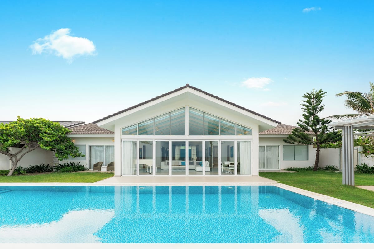 Une maison moderne dotée d’une piscine, de grandes fenêtres et d’une pelouse bien entretenue.