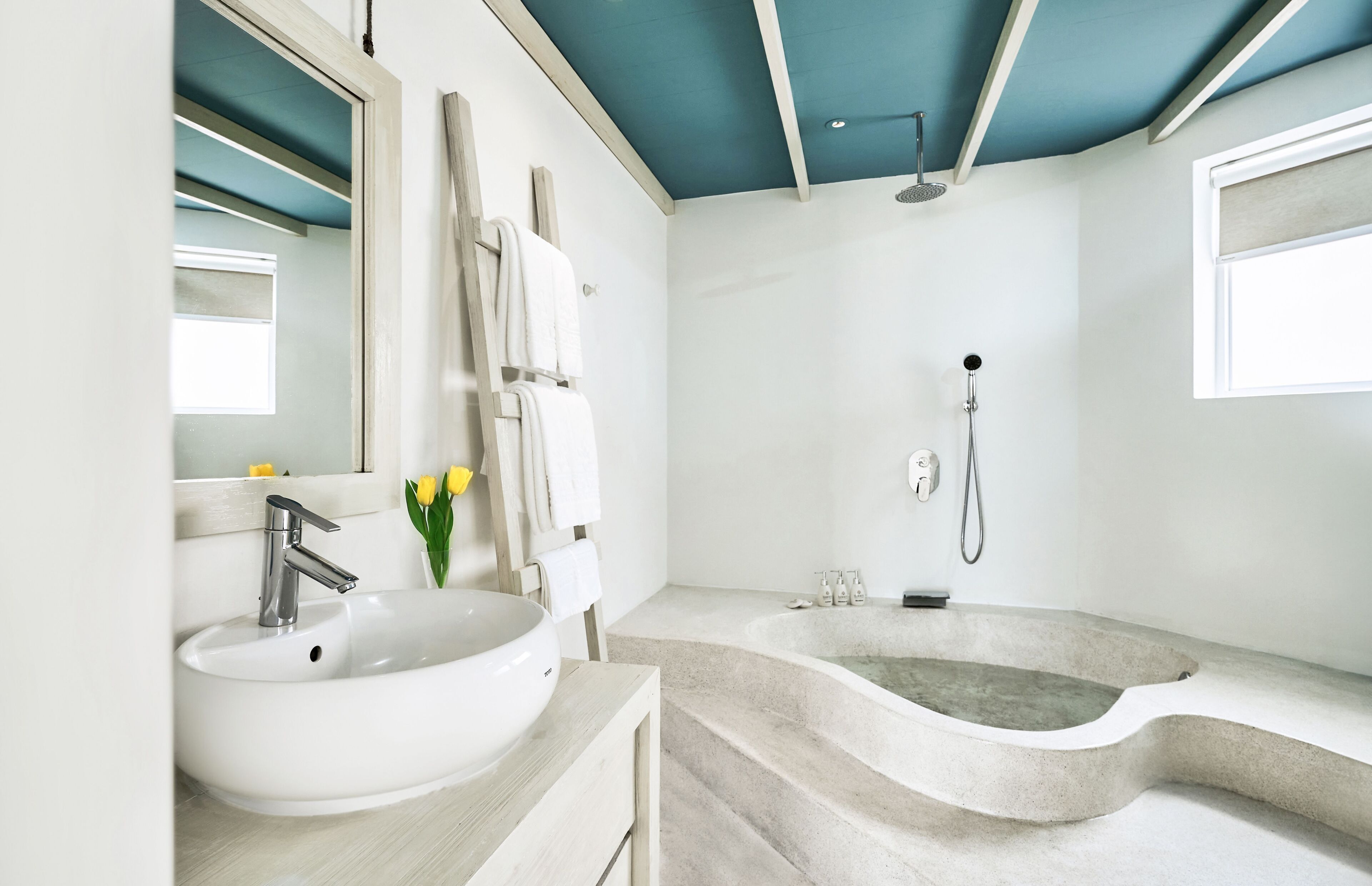 Un baño moderno con un lavabo blanco, una bañera independiente y una ducha.