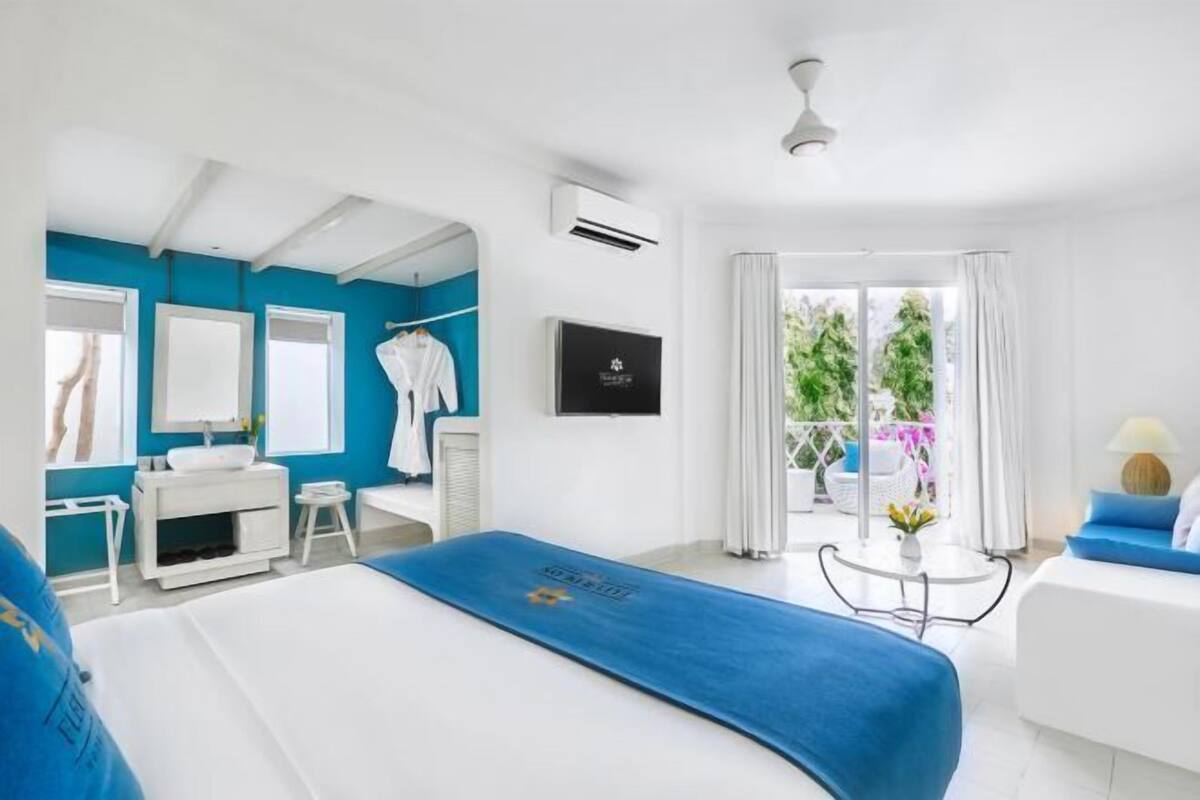 Une chambre d’hôtel avec un lit, un bureau, une chaise, une télévision et un balcon avec vue.