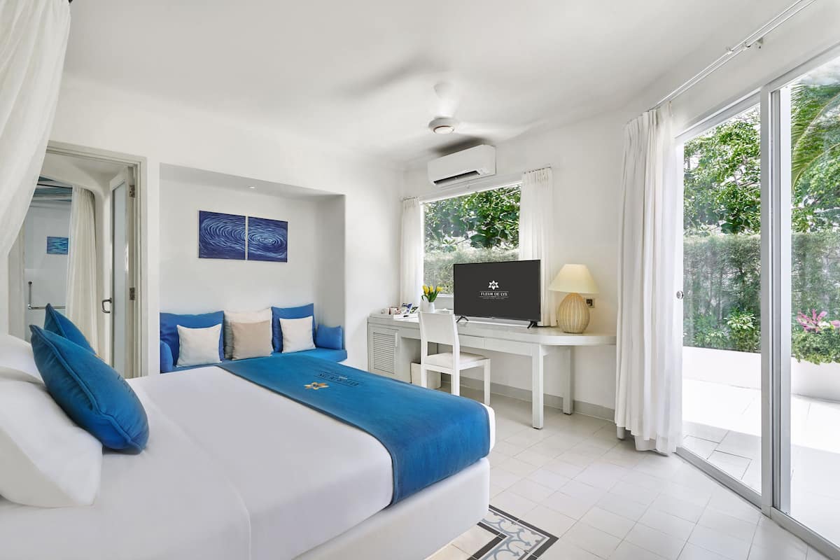 Une chambre avec un lit, un bureau, une télévision et une vue sur la verdure.