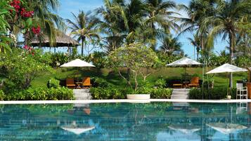 Una piscina al aire libre, sombrillas, sillones reclinables de piscina