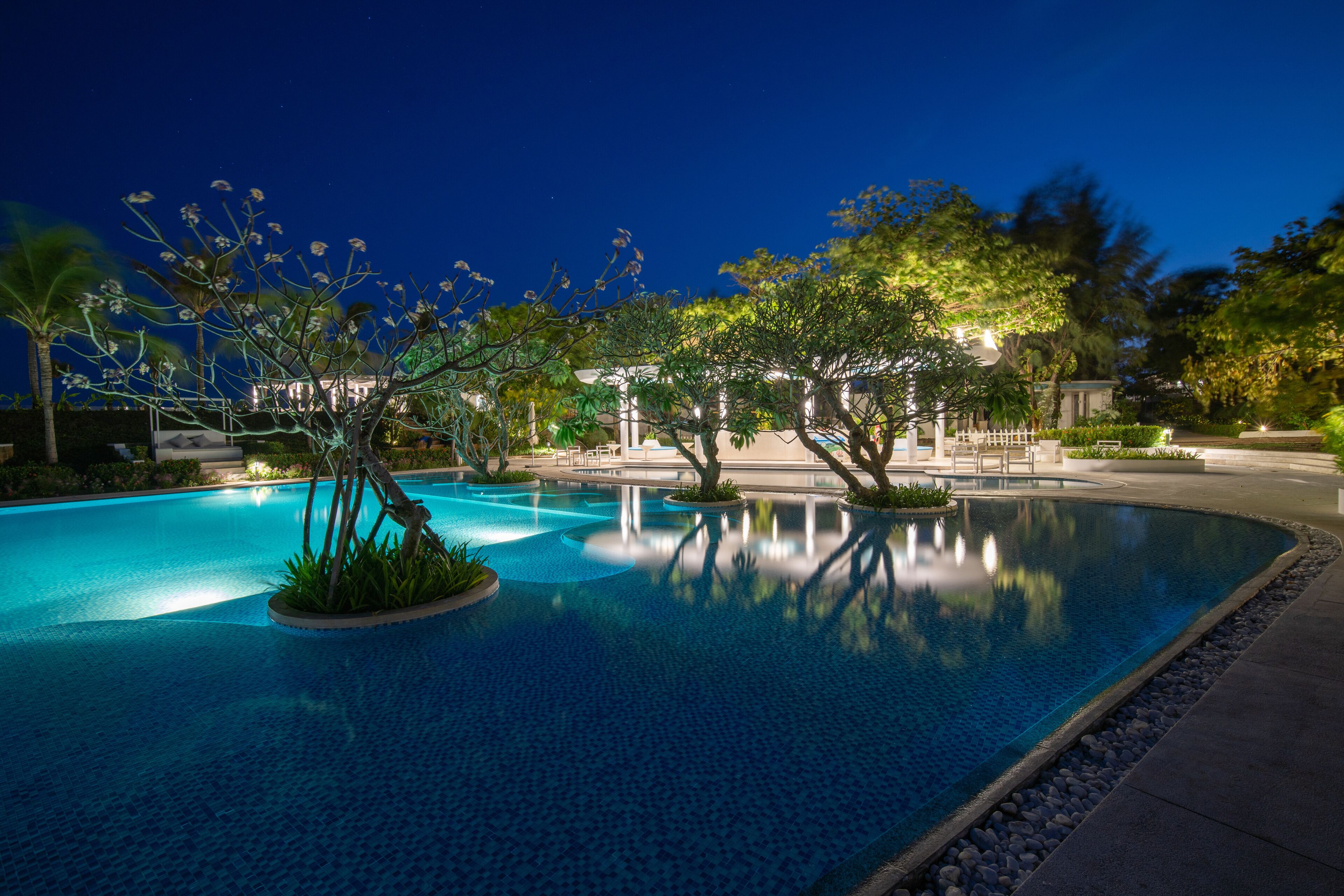 Una piscina al aire libre, sombrillas, sillones reclinables de piscina