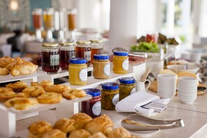 Un bufé de desayuno con pasteles, mermeladas y salsas.