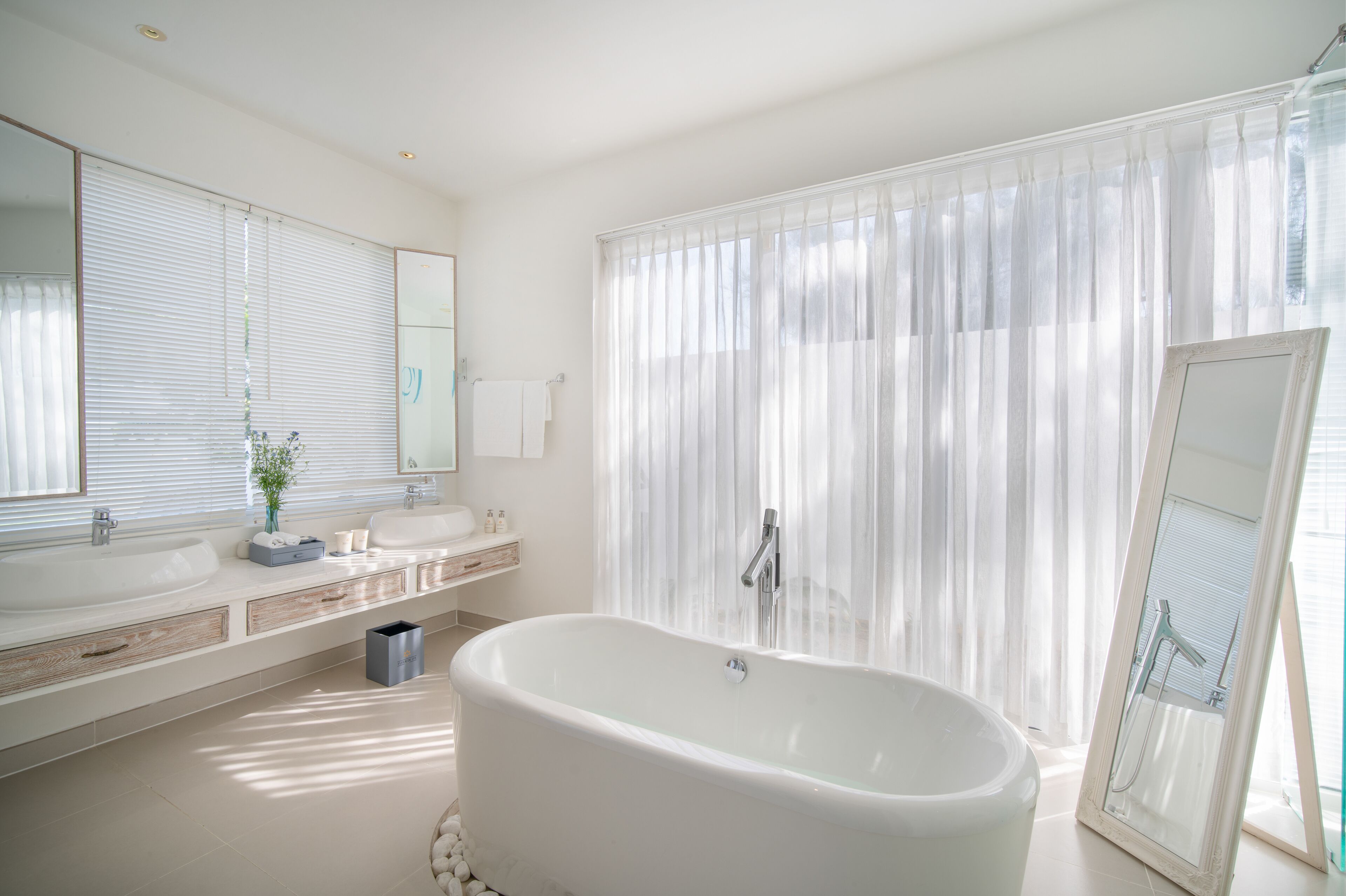 Un baño moderno con una bañera independiente, un espejo grande y una zona de ducha con cortinas.