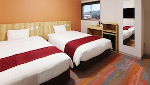 Hotelkamer met twee bedden, een houten hoofdbord, een klein bureau, een spiegel en een raam met uitzicht over de stad.