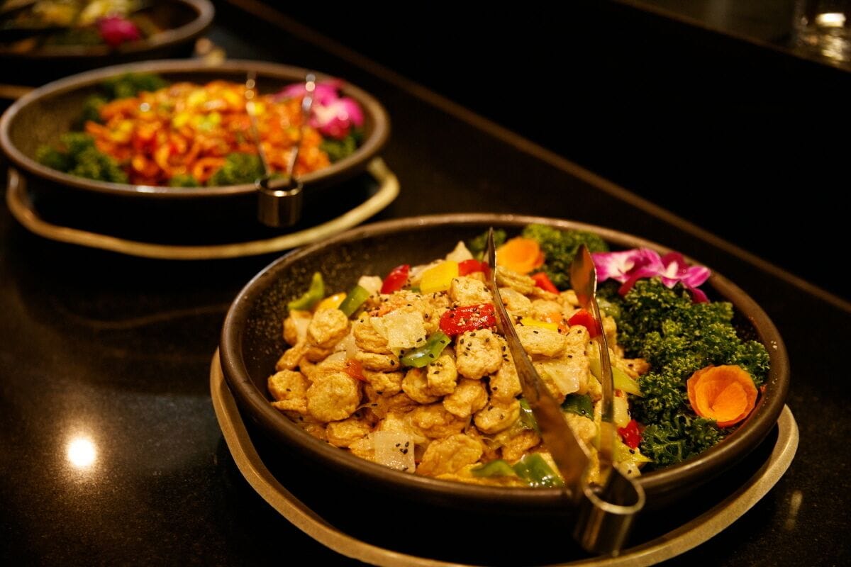 A dining table with multiple bowls of food, including a dish with tofu and vegetables.