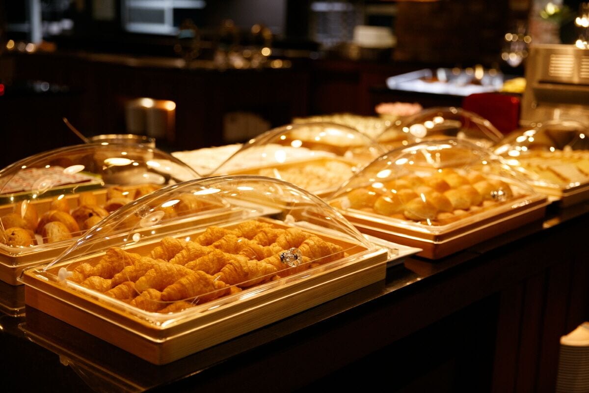 A buffet with various food items, including pastries and desserts, displayed in clear containers.