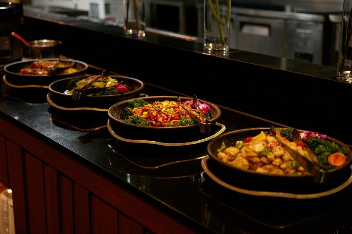 Un banco buffet con diversi piatti, tra cui insalate, carni e verdure.