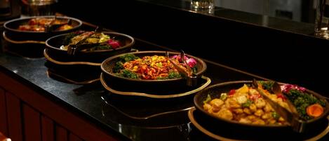 A buffet line with various dishes, including salads, meats, and vegetables, arranged on a counter.