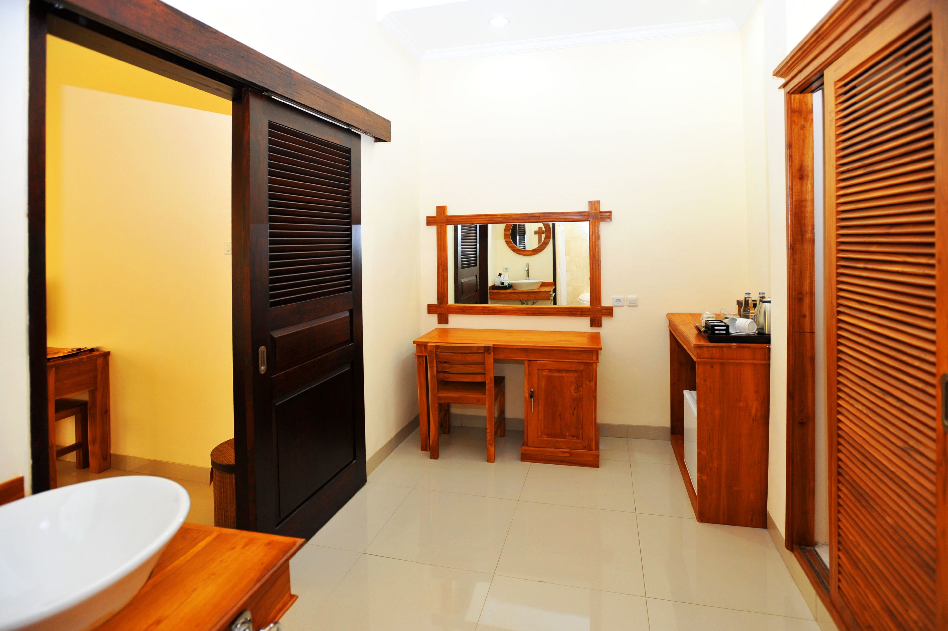 A bathroom with a wooden vanity, a sink, a mirror, and a toilet.