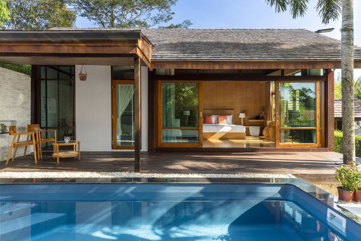 A modern house with a swimming pool, large glass doors, and a patio area.