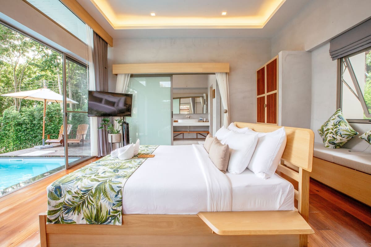 A bedroom with a large bed, a TV, and a view of a swimming pool.
