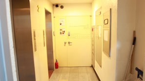 A hallway with a door marked "2" and a fire extinguisher on the floor. - Hostel Korea 10th (Seoul)
