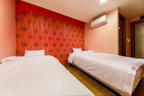 A hotel room with two single beds, a red patterned wall, and an air conditioning unit.