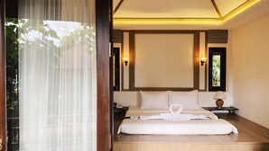 Ein Hotelzimmer mit Bett, Holzboden, einer Schiebetür aus Glas und einem Nachttisch mit Lampe.