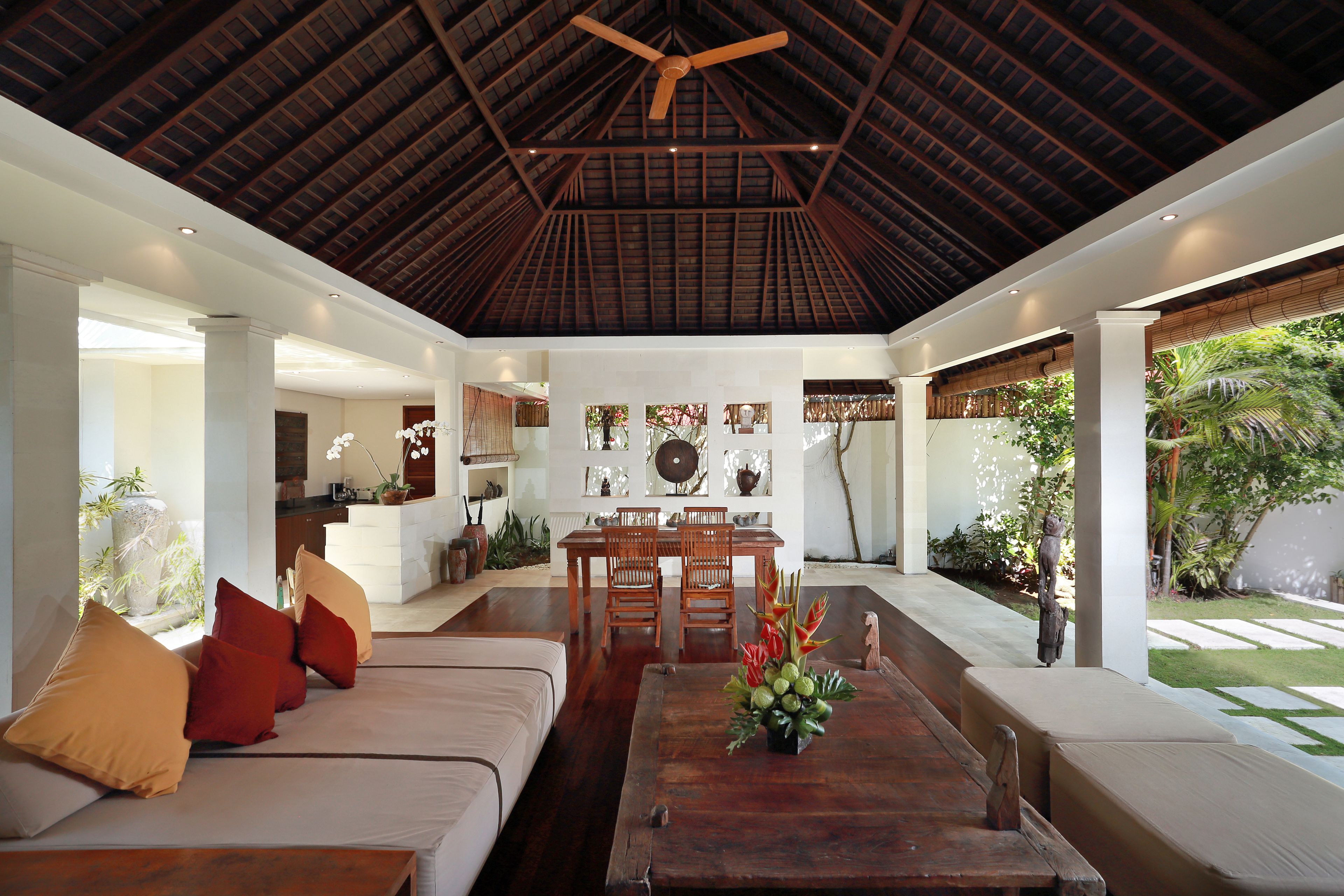A spacious living area with a high ceiling, a dining table, and a sofa with cushions.