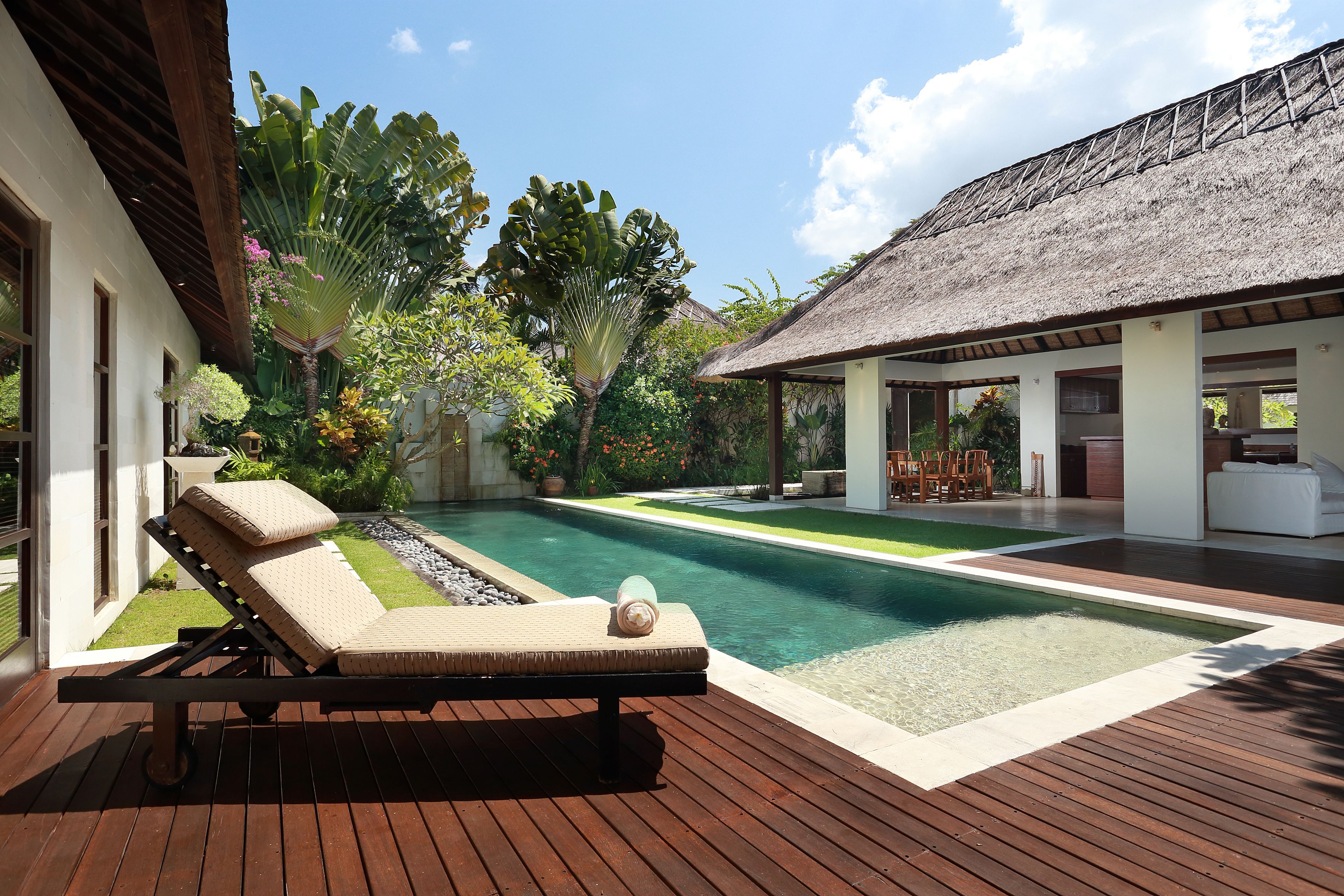 Una piscina al aire libre, sombrillas, sillones reclinables de piscina
