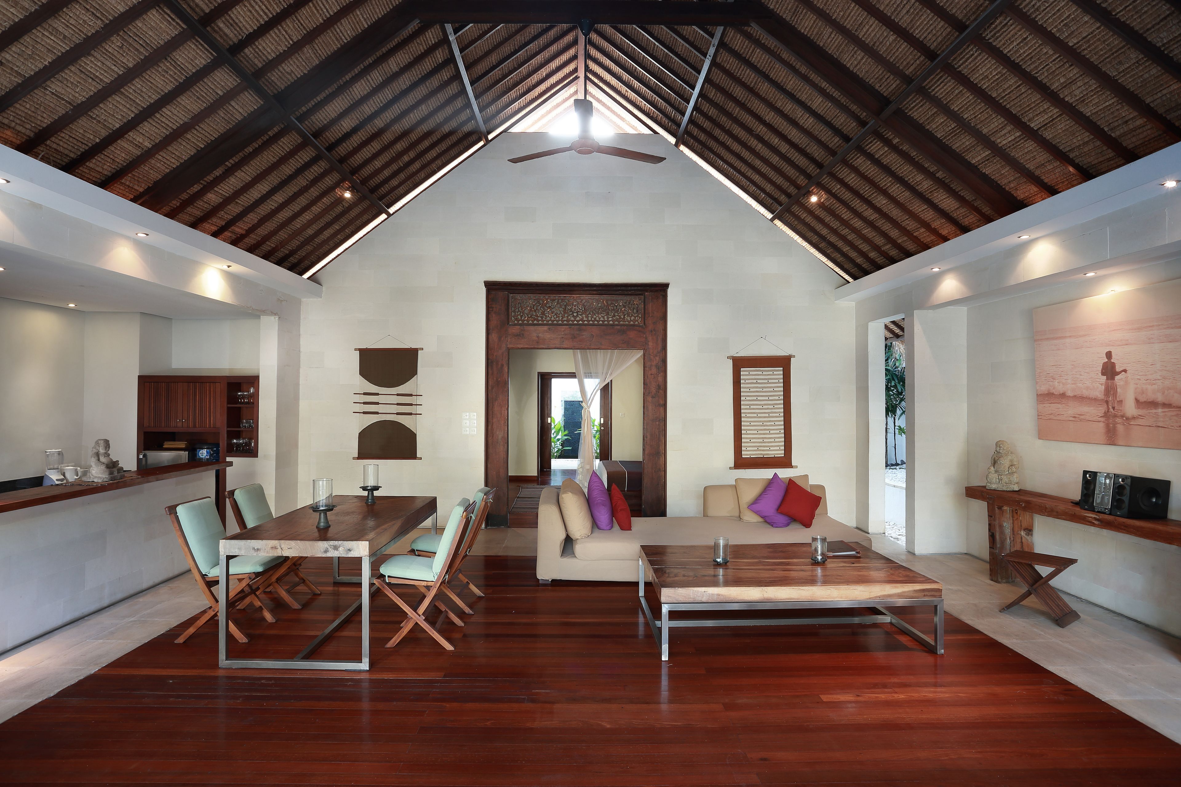 A spacious room with a high ceiling, a dining area, a sofa set, and a kitchen area.
