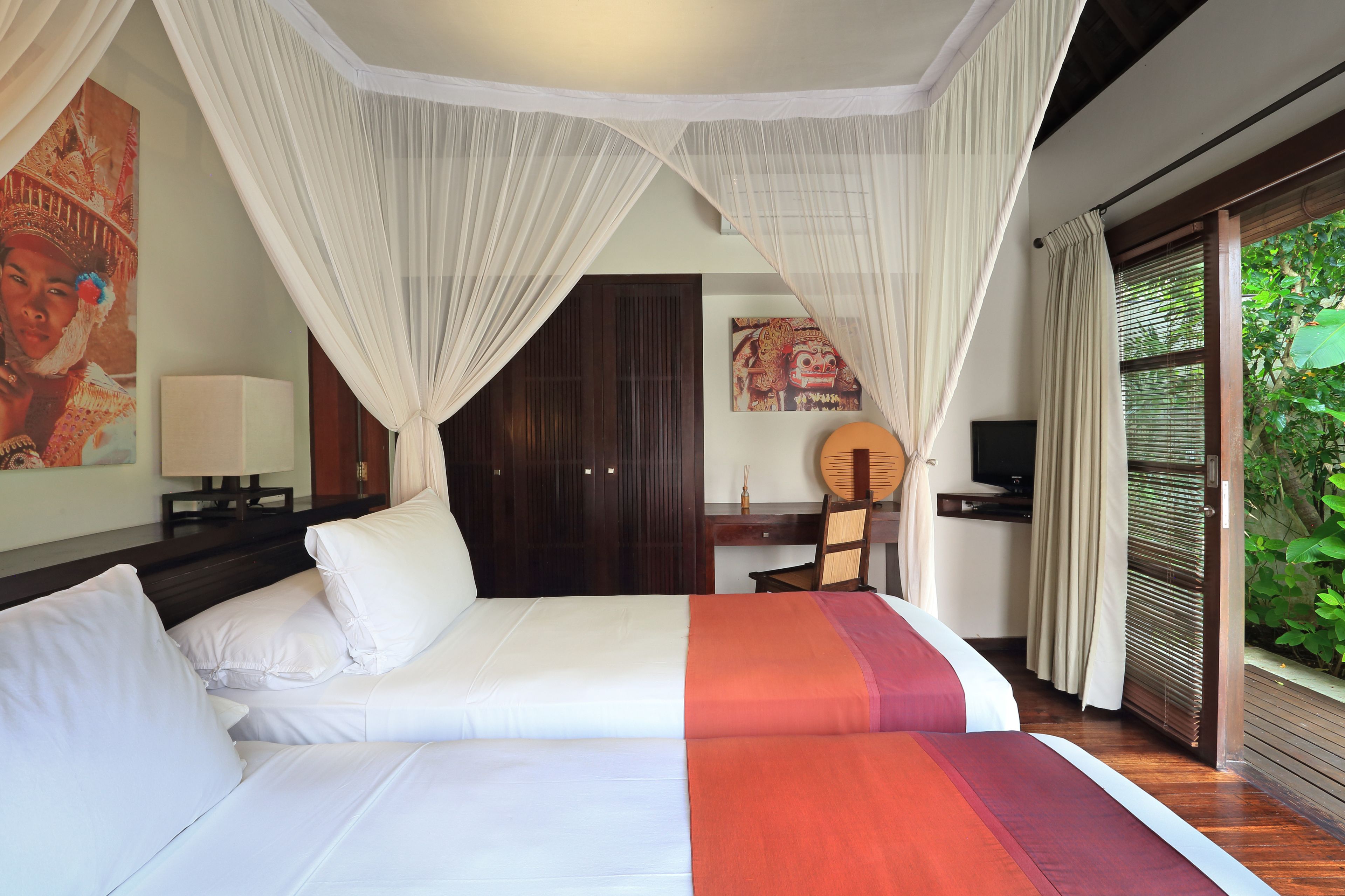 Quarto com cama, escrivaninha, cadeira e televisão.