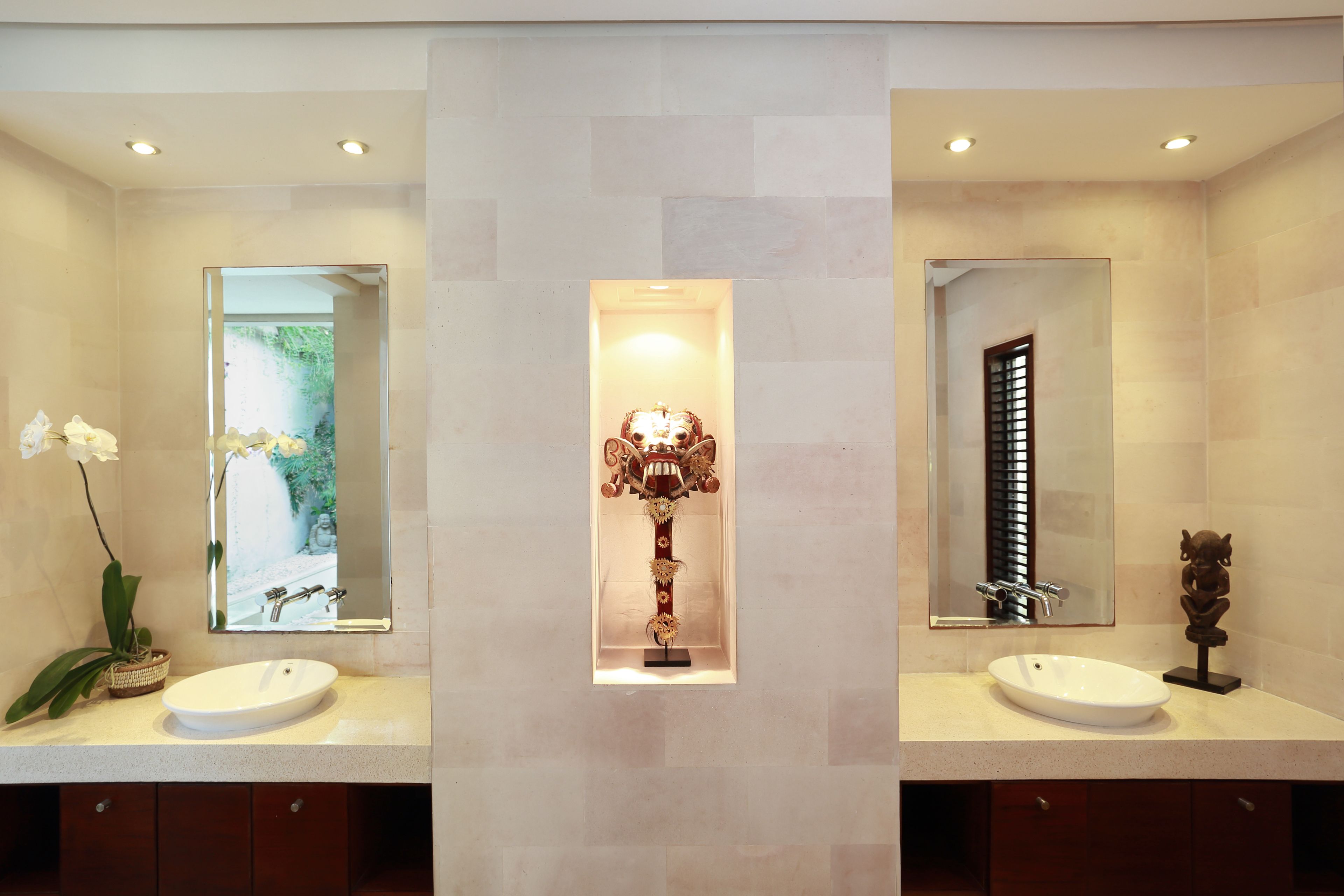 A modern bathroom with two sinks, a central decorative column, and a large mirror.