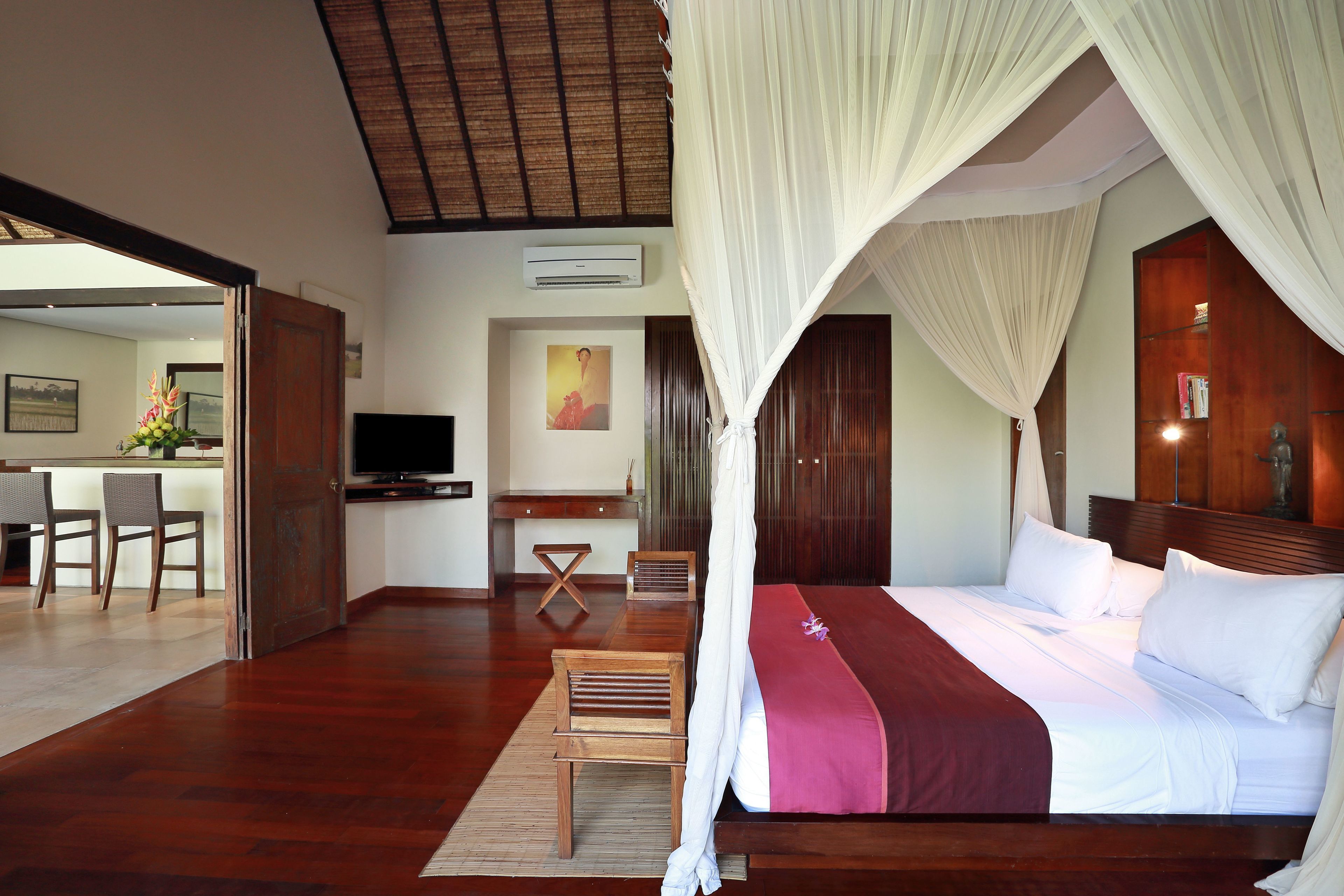A bedroom with a large bed, a TV, a desk, and a chair.