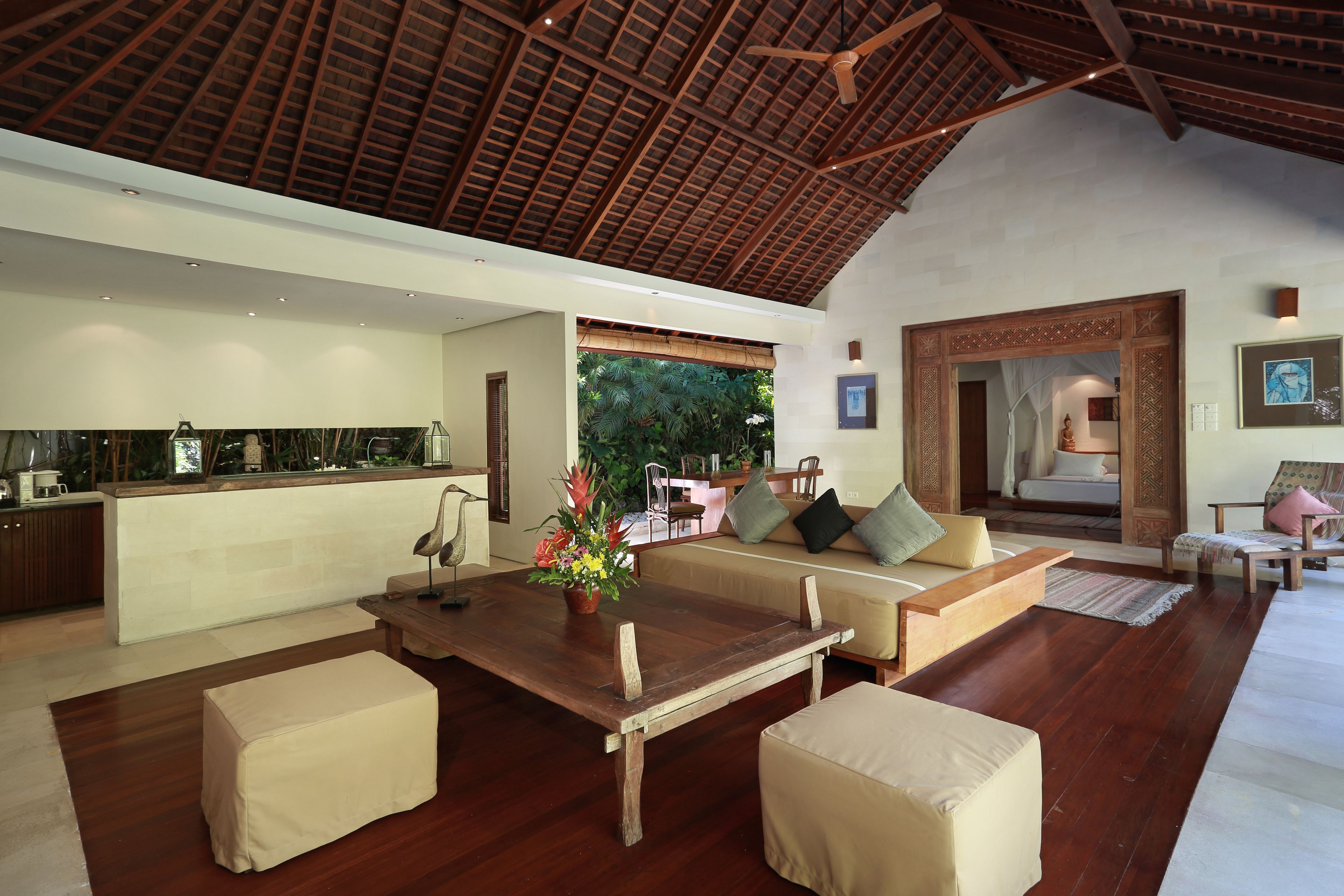 A spacious living area with a wooden dining table, cushioned seating, and a view of the outdoors.