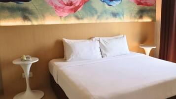 A hotel room with a large bed, two bedside tables, and a floral wall mural.