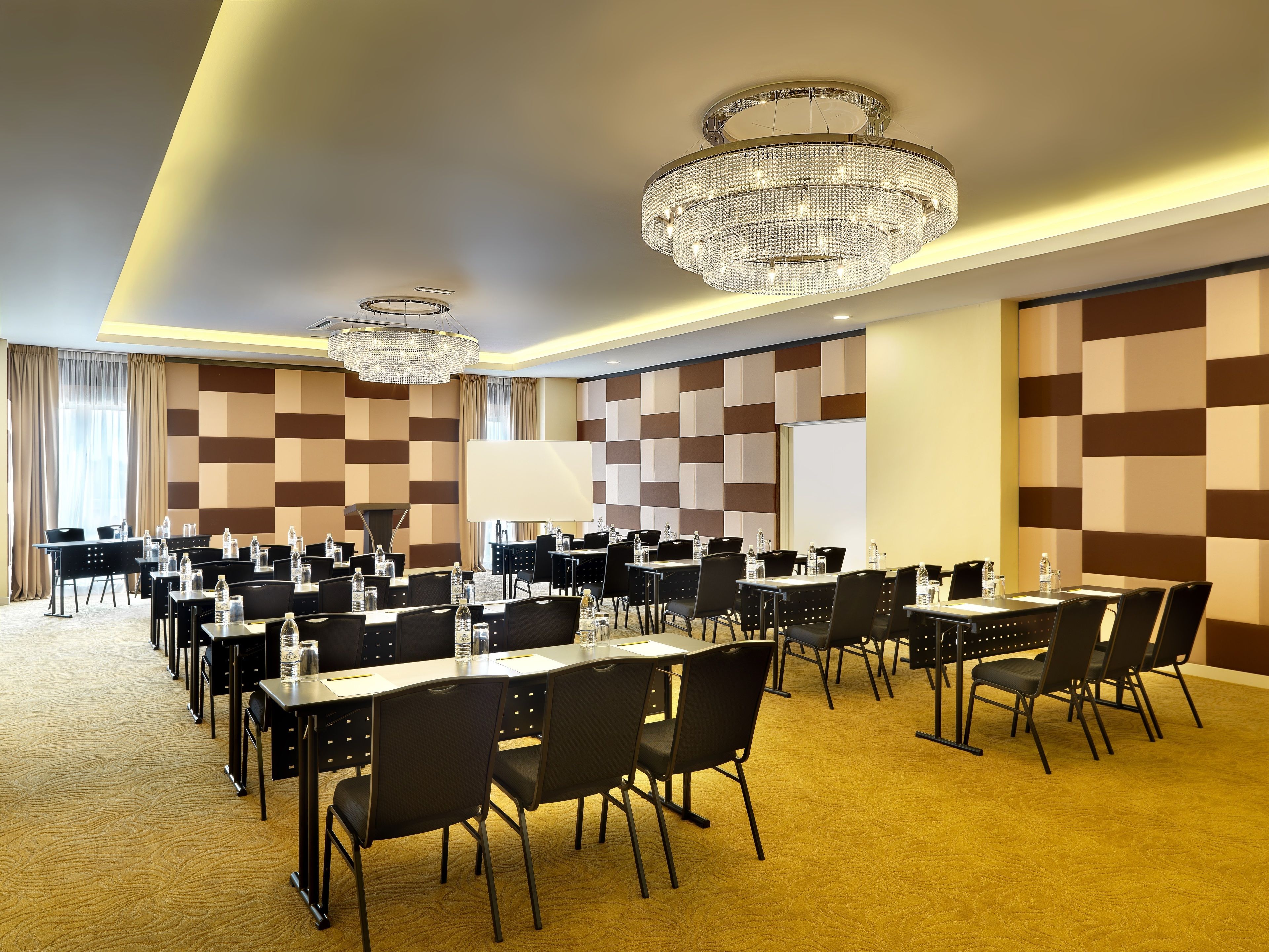 A conference room with multiple tables, chairs, and a large screen.