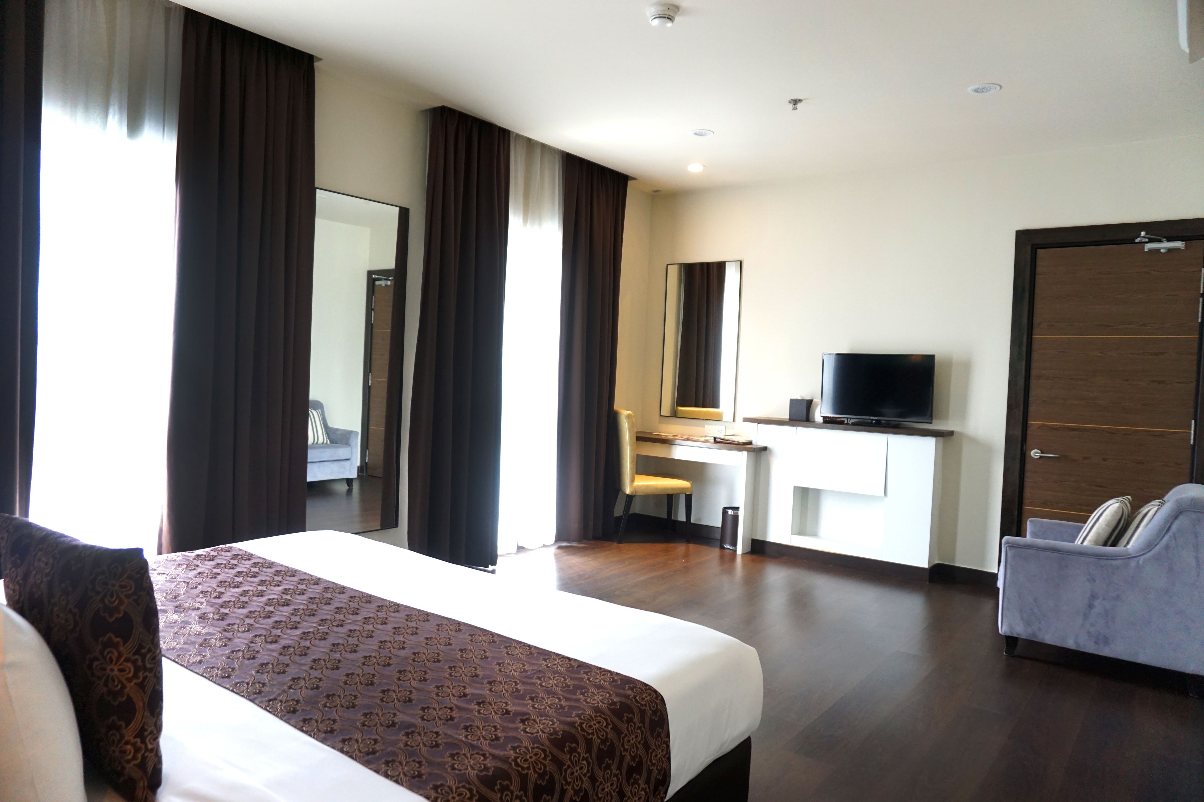 Une chambre d’hôtel avec un grand lit, un bureau avec une chaise, une télévision et une armoire.