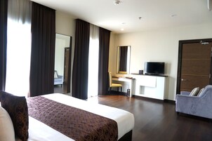Une chambre d’hôtel avec un grand lit, un bureau avec une chaise, une télévision et une armoire.