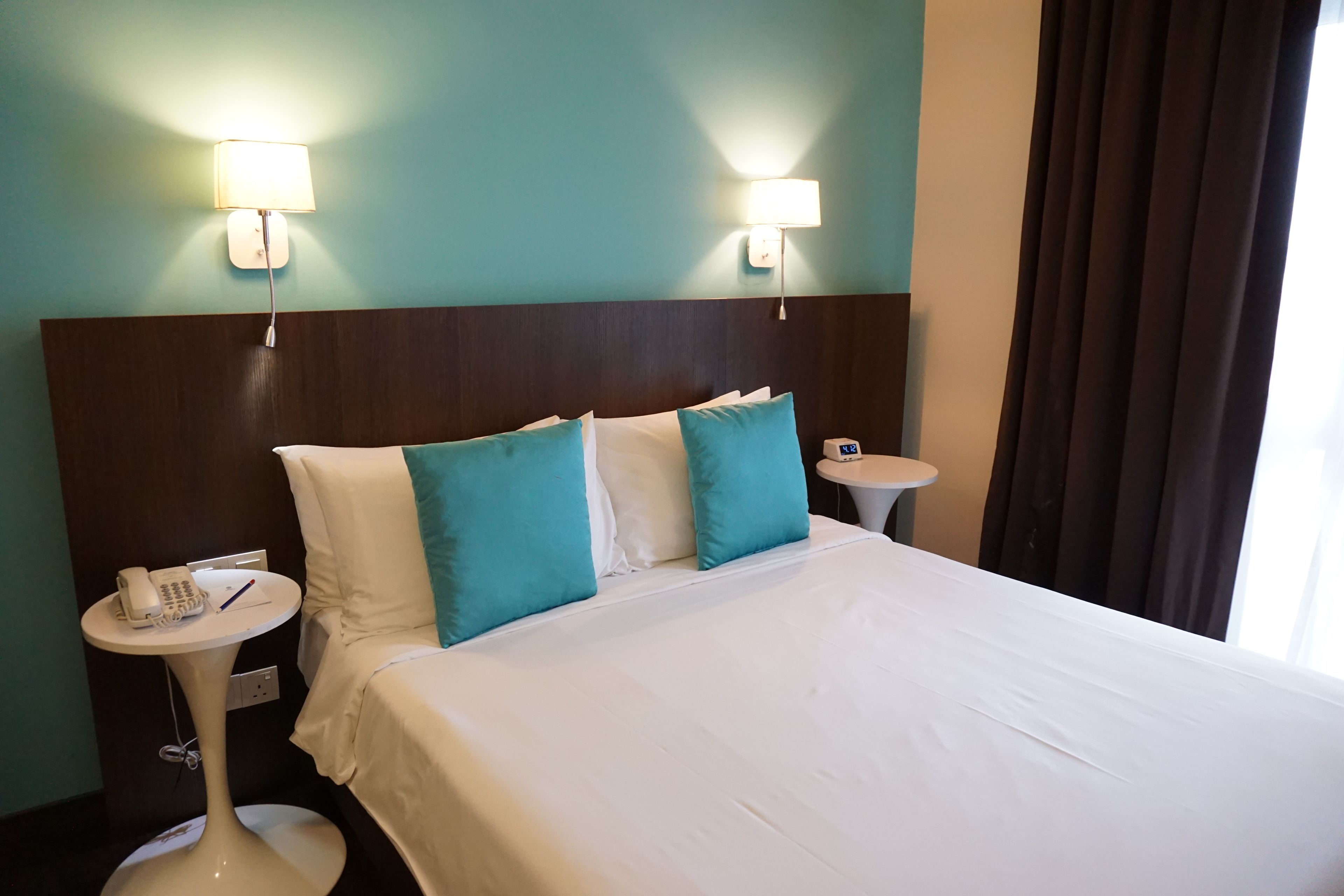 A hotel room with a large bed, two bedside tables, a phone, and a lamp on each side.