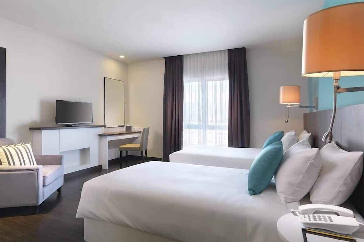 A hotel room with two beds, a desk, a TV, and a phone.
