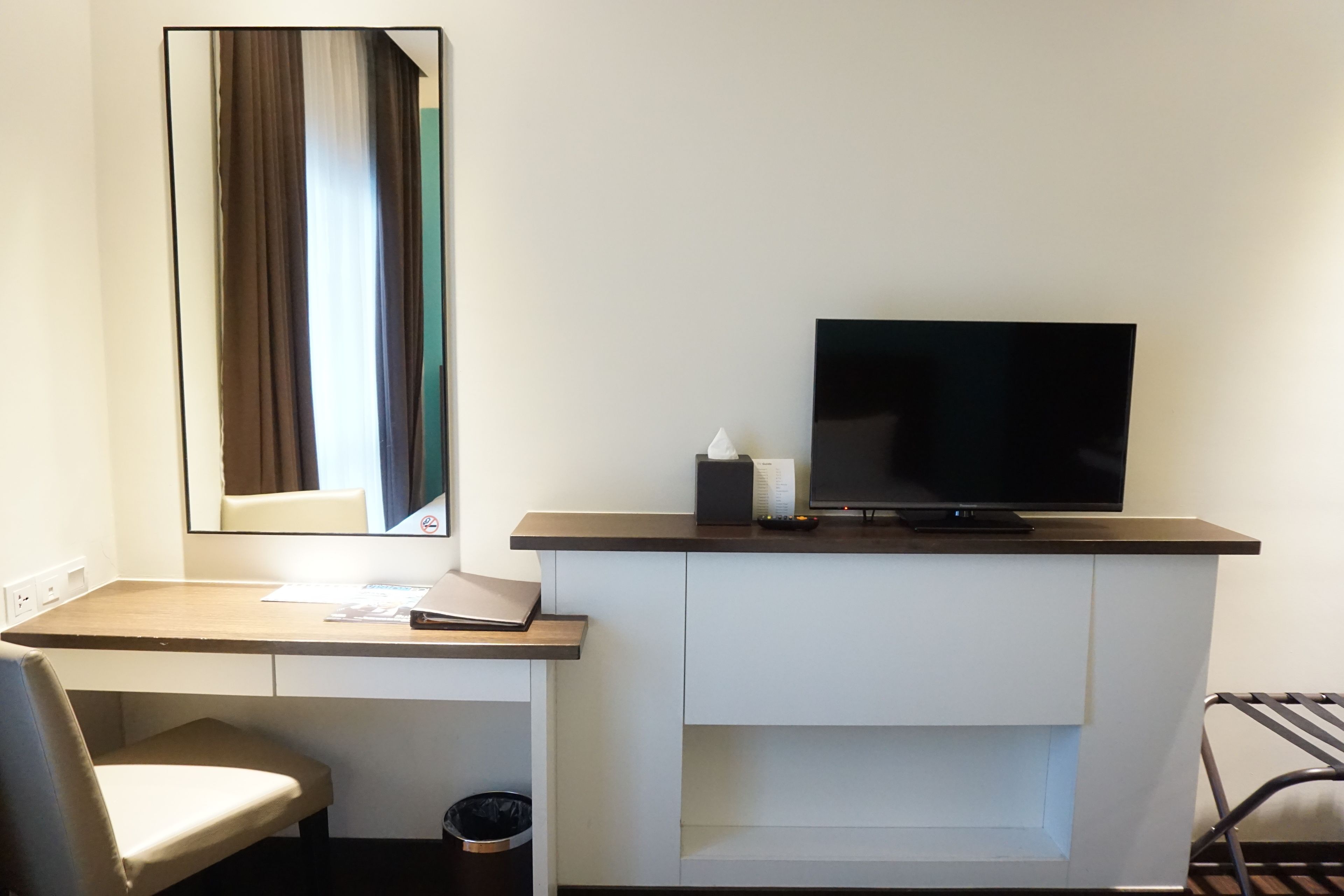 Habitación de hotel con escritorio, silla, televisión y espejo.