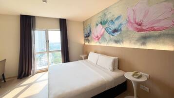 Ein Hotelzimmer mit einem großen Bett, einem Nachttisch mit Telefon und einem Fenster mit Vorhängen.