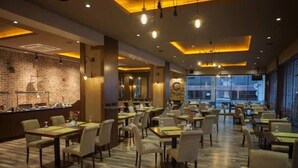 Un restaurante espacioso con varias mesas y sillas, una pared de ladrillo y un ventanal grande.