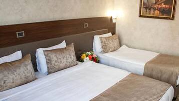 Habitación de hotel con dos camas, un cabecero, una mesita de noche y un cuadro en la pared.