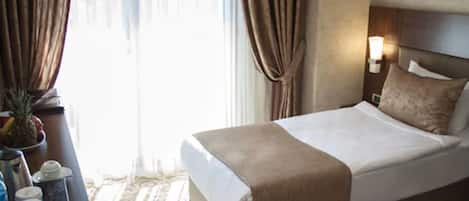 Habitación de hotel con una cama grande, una mesita de noche, una lámpara y vistas al exterior.