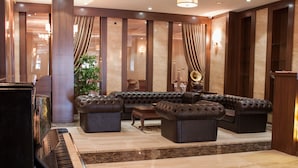 Un amplio salón con un piano de cola, un sofá modular y una almohada decorativa roja.