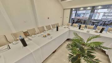 A conference room with a long table, chairs, and a potted plant.