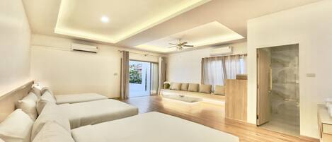 A modern hotel room with two beds, a sofa, a ceiling fan, and an air conditioning unit.